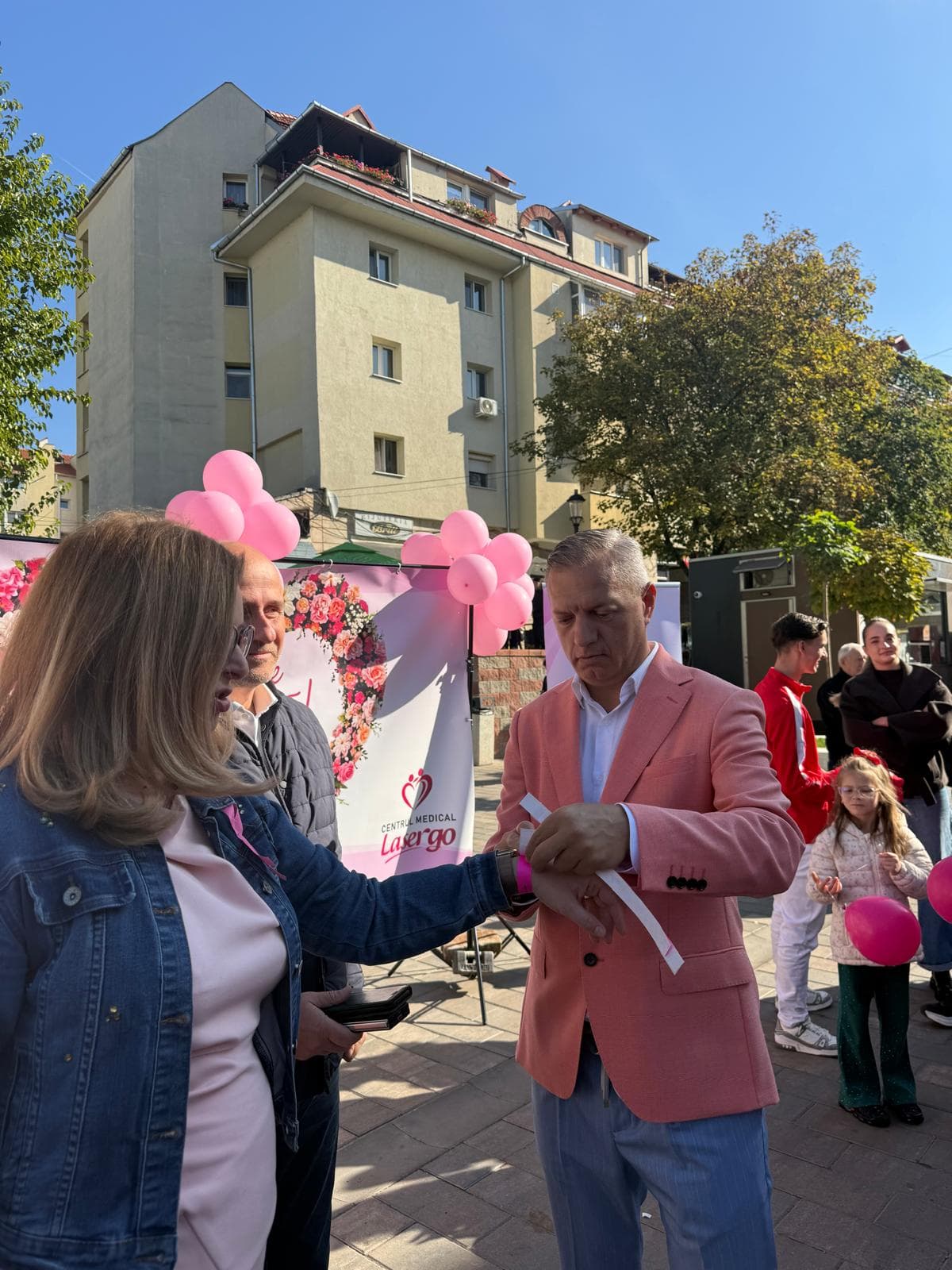 Dr. Iluță Sorin Gabriel prinde o brățară roz pe mâna unei participante la campanie