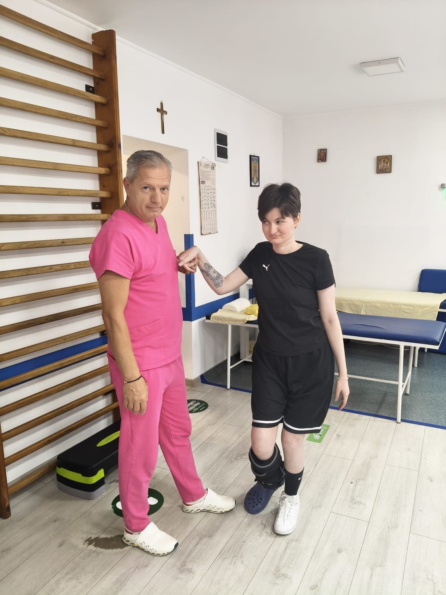 Dr. Iluță Sorin Gabriel evaluează mersul unei paciente în sala de recuperare