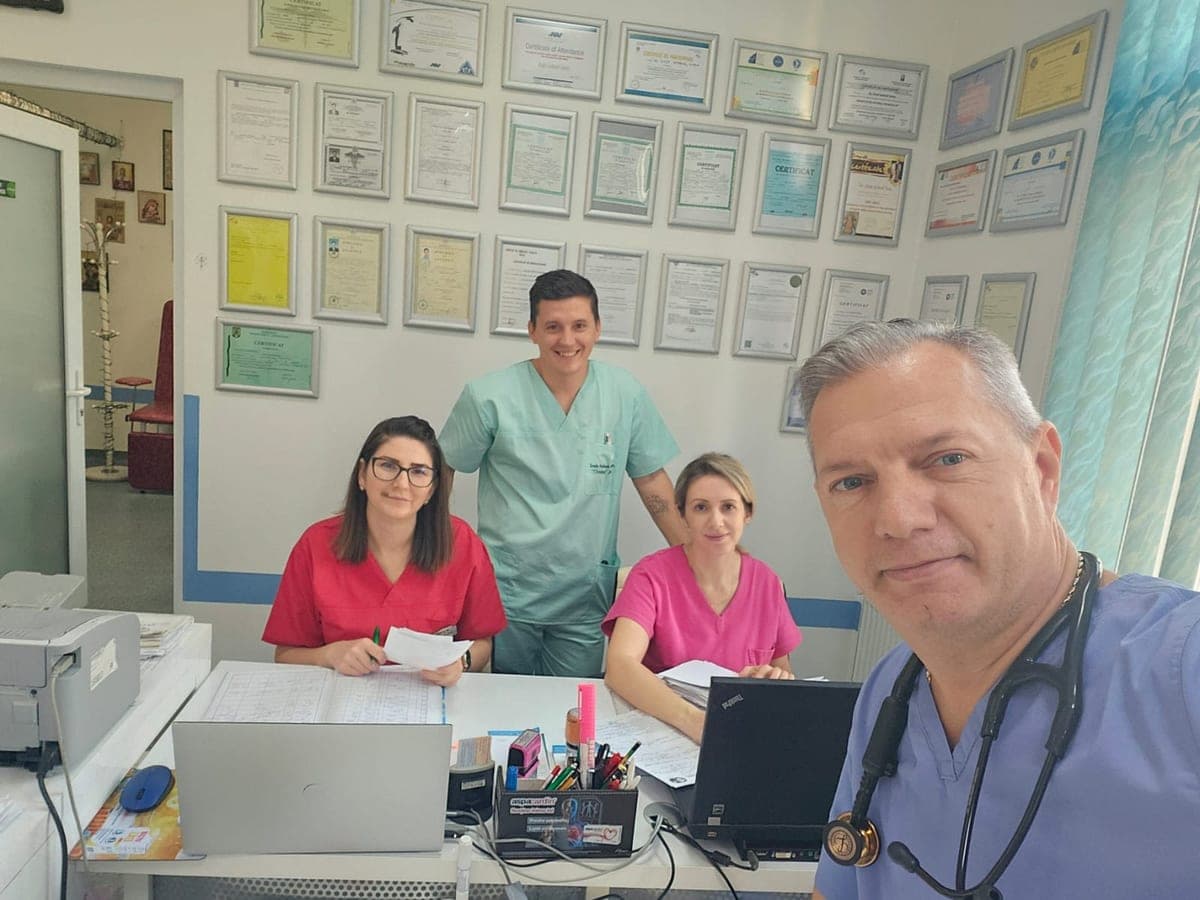 Echipa cabinetului la recepție: medicul în față, alături de asistente și de un coleg, sub diplomele de pe perete