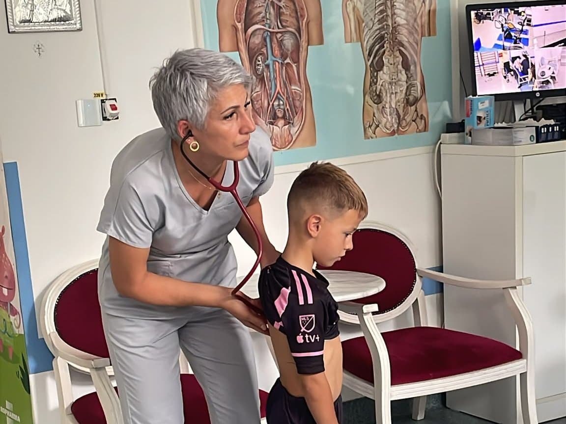 Medicul pneumolog ascultă cu stetoscopul respirația unui copil, în cabinet