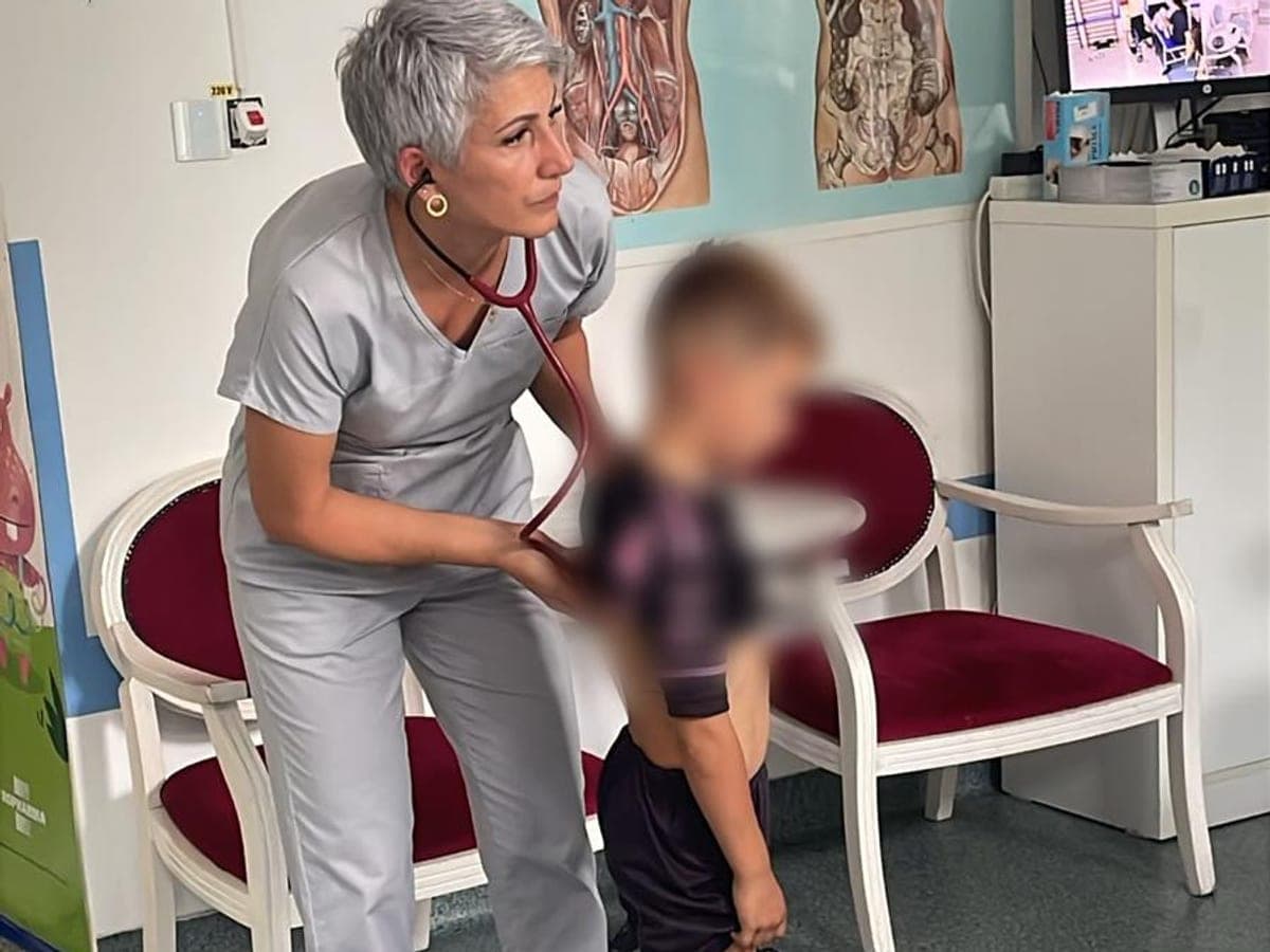 Medicul pneumolog ascultă cu stetoscopul respirația unui copil, în cabinet