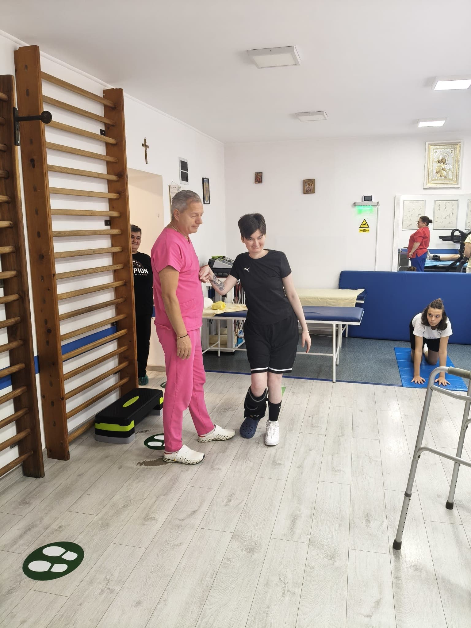 Pacientă la exerciții de mers, ajutată de medic, în sala de kinetoterapie Lasergo