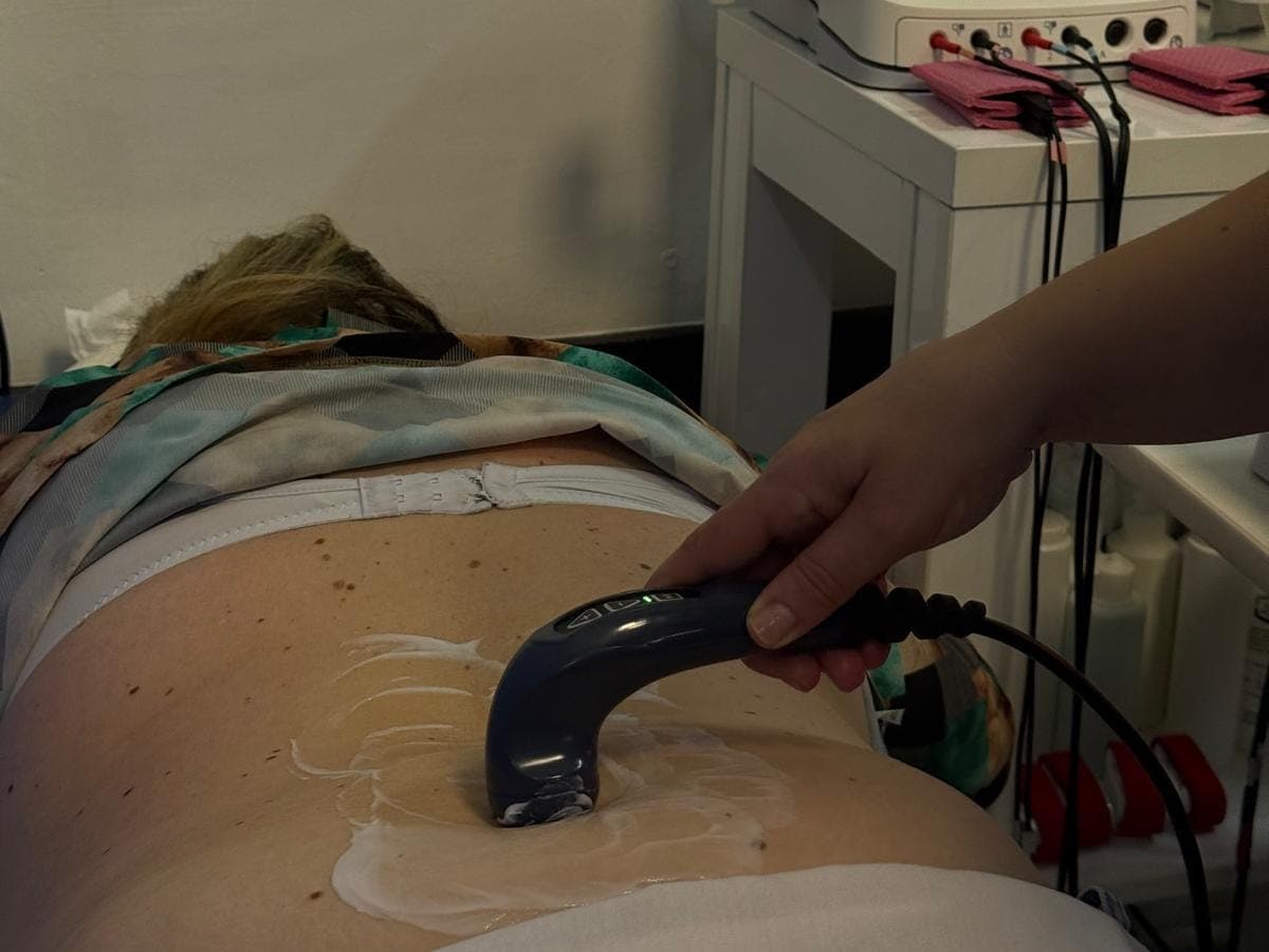 Aplicatorul TECAR trecut peste zona lombară a unei paciente întinse pe burtă